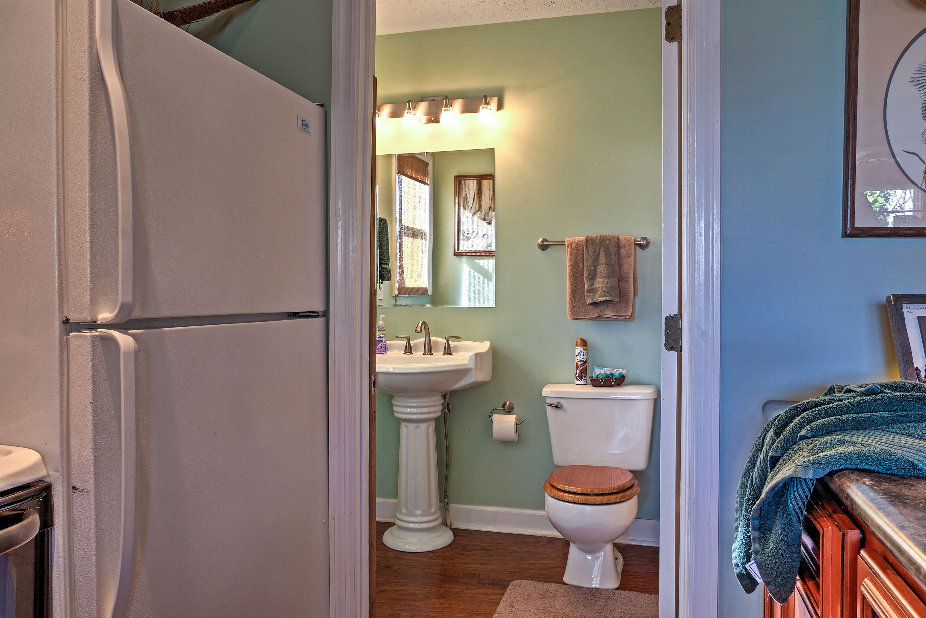 A bathroom with a pedestal sink, toilet, and a mirror above the sink.