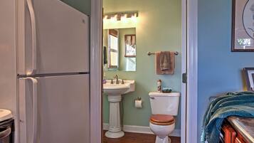 A bathroom with a pedestal sink, toilet, and a mirror above the sink.