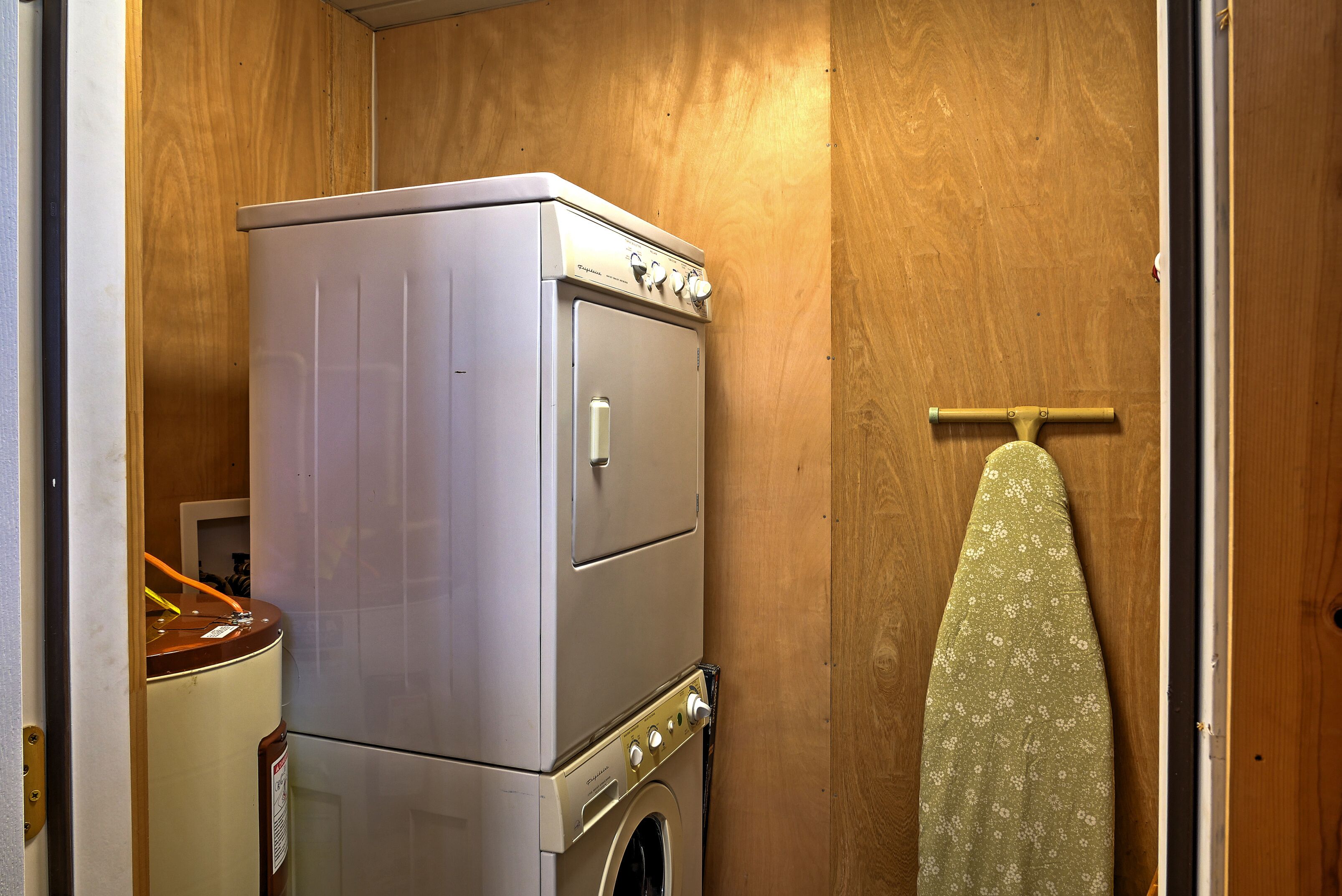 A compact laundry room with a washer and dryer, a wooden door, and a towel rack.