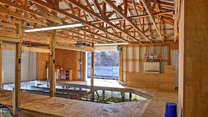 A spacious room with a high ceiling, wooden beams, and a large window. - 'paradise Cove' Cabin w/ Boathouse & Dock (Guntersville)