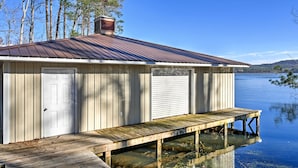 A wooden dock extending into a calm lake, with a metal roofed building adjacent to it. - 'paradise Cove' Cabin w/ Boathouse & Dock (Guntersville)