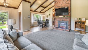 A spacious living room with a fireplace, a dining area, and a large TV mounted on a brick wall. - Newcomb Retreat w/ Mountain Views & Fire Pit! (Newcomb)