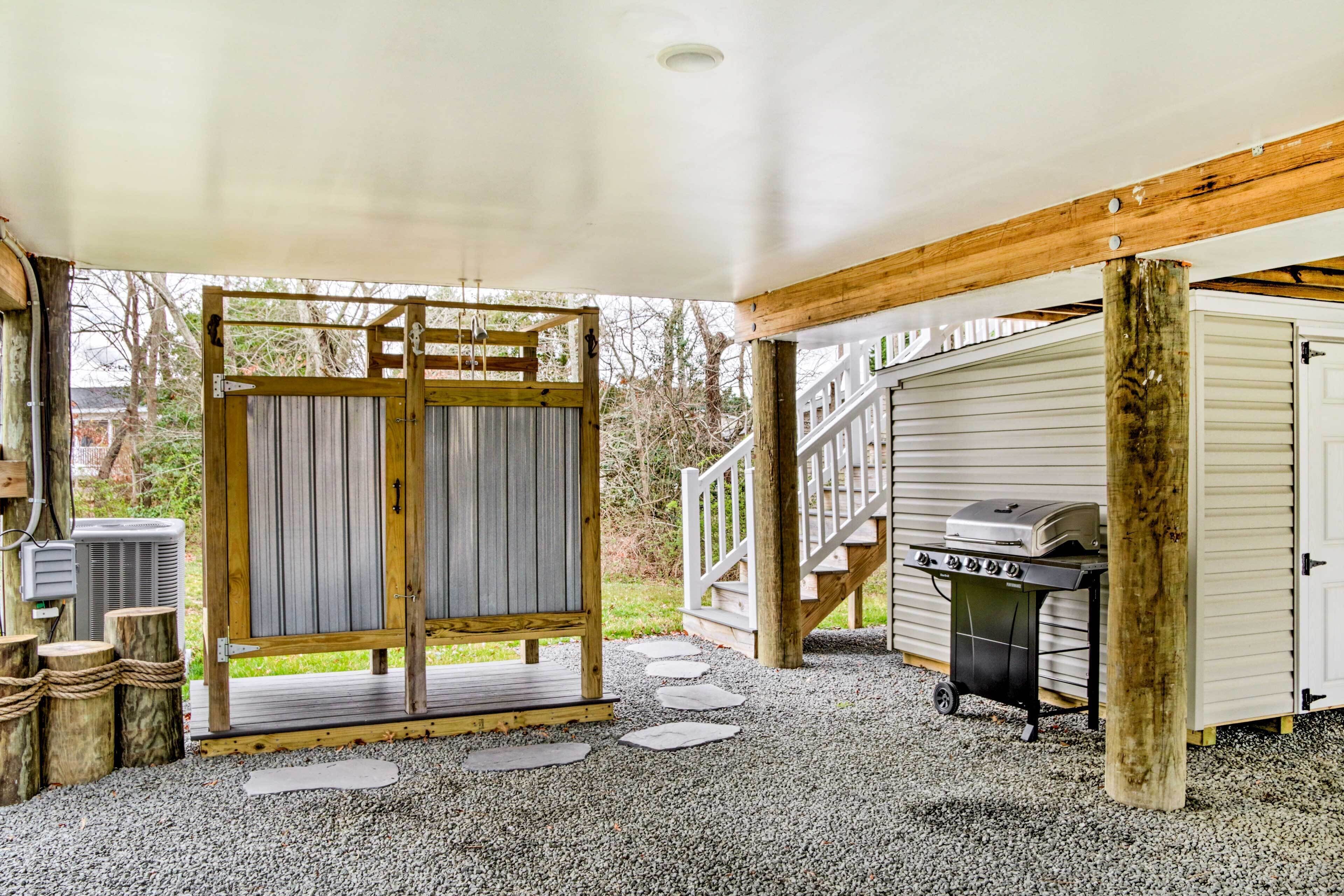 Un espace extérieur abrité doté d’une terrasse en bois, d’un barbecue et d’une porte de garage.