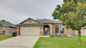 A residential house with a garage, brick exterior, and a lawn with a tree. - Temple Retreat: Game Room & Deck, Pets Welcome (Temple)