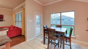 A dining area with a table and chairs, a red couch, and a window with a view of the backyard. - Temple Retreat: Game Room & Deck, Pets Welcome (Temple)
