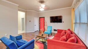 A living room with a red sofa, blue armchairs, a coffee table, and a ceiling fan. - Temple Retreat: Game Room & Deck, Pets Welcome (Temple)