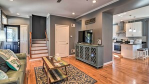 A modern living room with a sofa, coffee table, and patterned rug. A staircase leads to another level. - Quaint Ligonier Family Home - 3 Miles to Idlewild! (Ligonier)