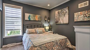 A bedroom with a bed, a nightstand, a lamp, and artwork on the walls. - Quaint Ligonier Family Home - 3 Miles to Idlewild! (Ligonier)