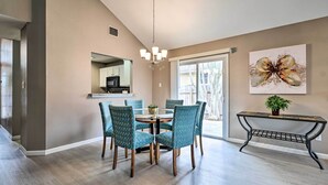 A dining area with a round table and chairs, a chandelier, a wall-mounted mirror, and a large window. - Peaceful Austin Home w/ Private Backyard! (Austin)