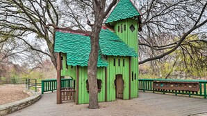 A green wooden structure with a peaked roof and multiple windows, surrounded by a wooden deck and a green railing. - Peaceful Austin Home w/ Private Backyard! (Austin)