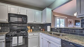 A modern kitchen with white cabinets, a black stove, a microwave, and a dishwasher. - Peaceful Austin Home w/ Private Backyard! (Austin)