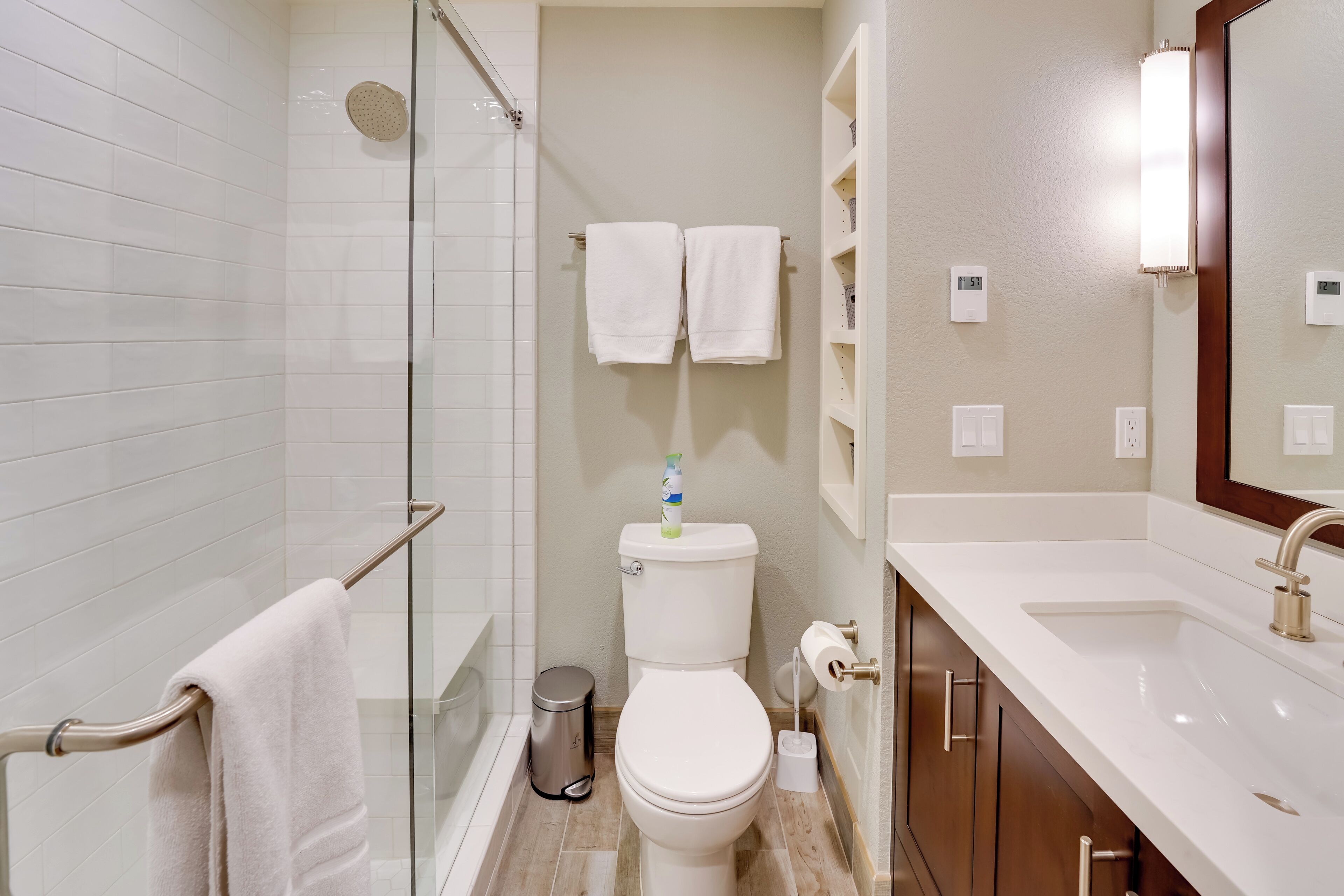 A modern bathroom with a glass shower enclosure, a toilet, a sink, and a mirror.