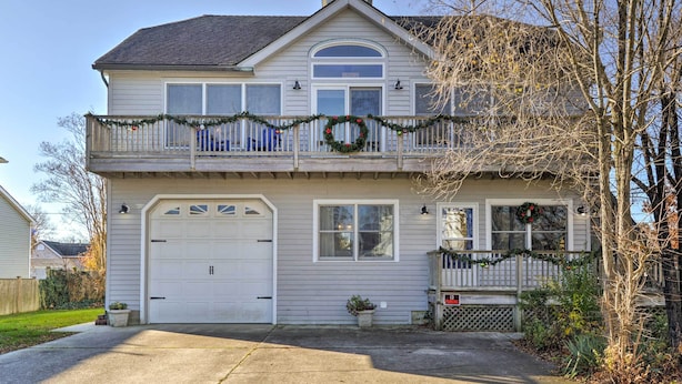 A two-story house with a garage, a balcony with a railing, and a front porch. - Serene West Cape May Getaway: Walk to Beach! (Cape May)