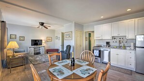 A modern living room with a TV, sofa, and dining table with placemats. - Serene West Cape May Getaway: Walk to Beach! (Cape May)