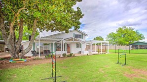 A house with a covered porch, a fenced yard, and a tree.