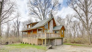 Eine zweistöckige Blockhütte mit Balkon, Steinofen und Garage.