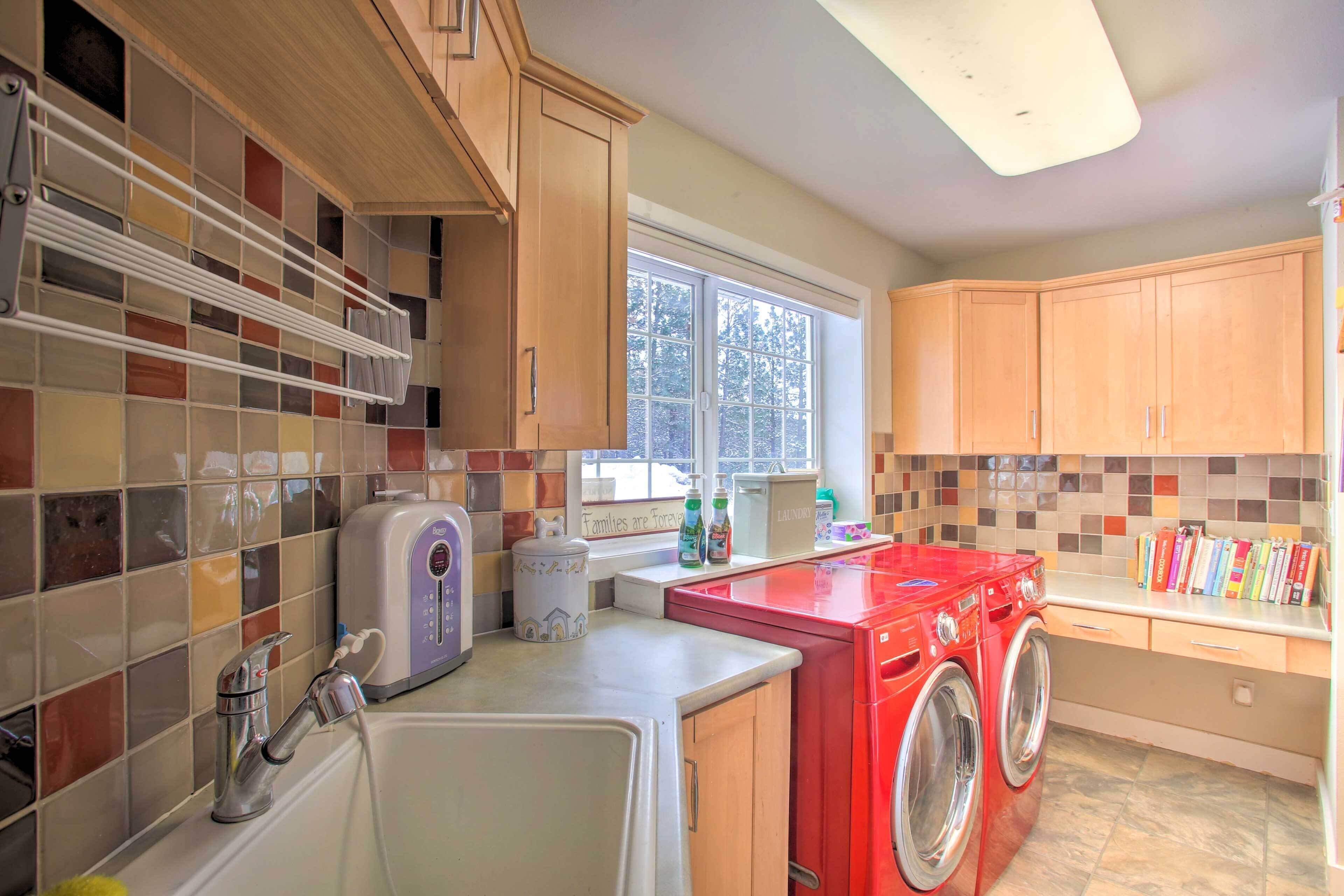 A laundry room with a washing machine, dryer, and a window with a view of trees.