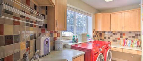 A laundry room with a washing machine, dryer, and a window with a view of trees.