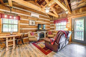 L’intérieur d’une cabane en rondins, avec une cheminée, un canapé en cuir et un plancher en bois.