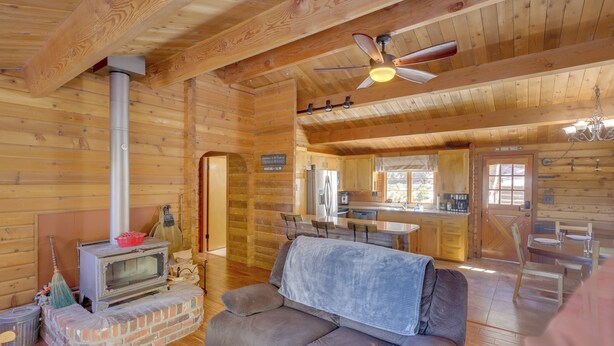 A cozy cabin interior with a fireplace, sofa, dining area, and kitchen. - Pine Mountain Club Cabin Rental w/ Pool Access! (Pine Mountain Club)
