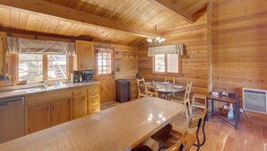 A wooden cabin interior with a kitchen, dining area, and a large window. - Pine Mountain Club Cabin Rental w/ Pool Access! (Pine Mountain Club)