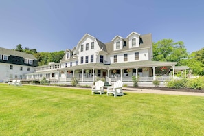 A large, multi-story building with a porch and outdoor seating area. - Pool + Hot Tub Access! Portage Lake Condo w/ Deck (Onekama)