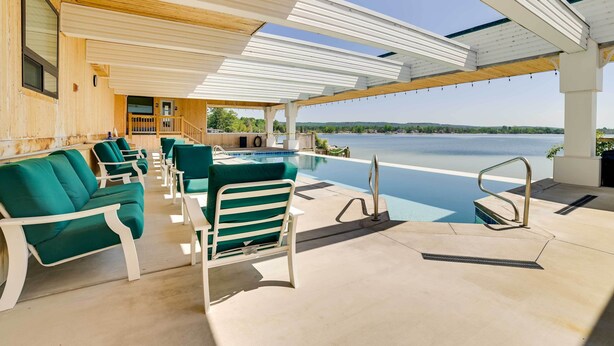 A poolside area with lounge chairs and a view of a lake. - Pool + Hot Tub Access! Portage Lake Condo w/ Deck (Onekama)
