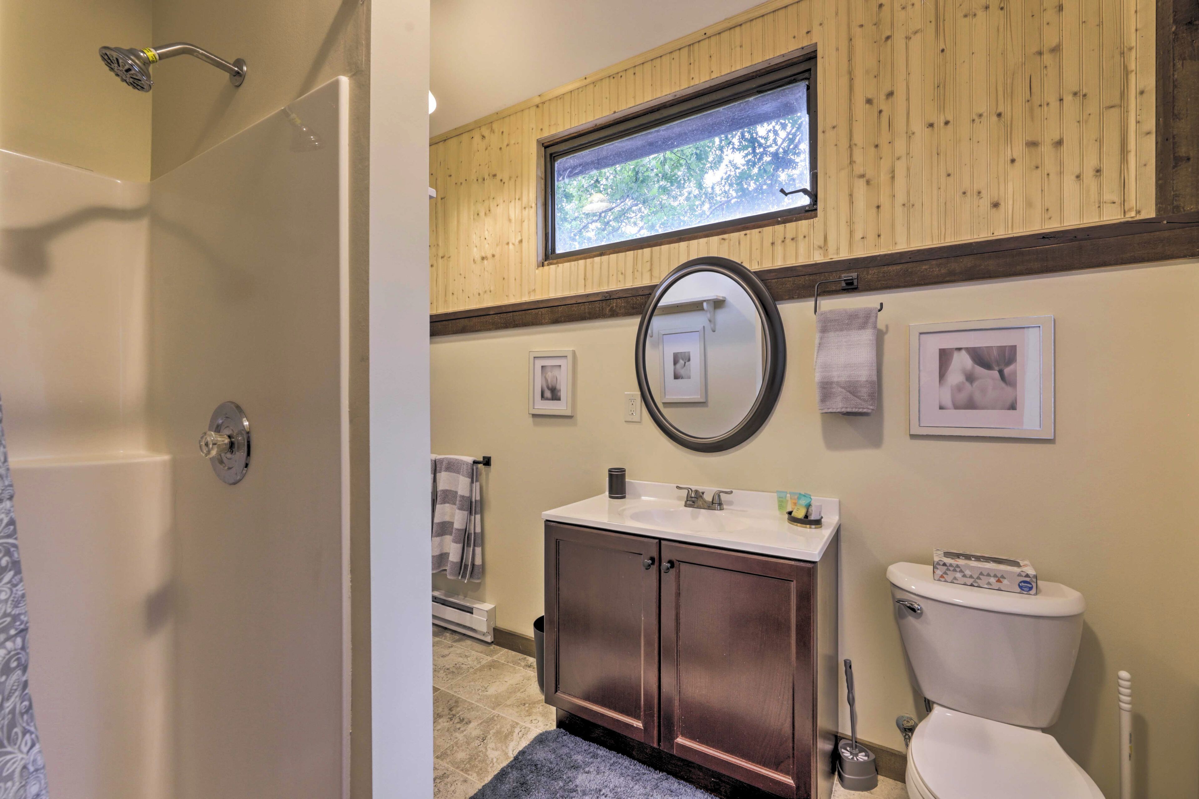 A bathroom with a shower, a sink, a toilet, and a window.