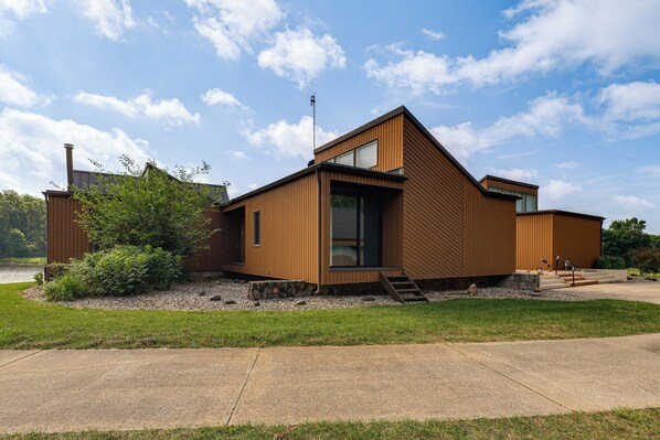 A modern house with a sloped roof, large windows, and a visible chimney.