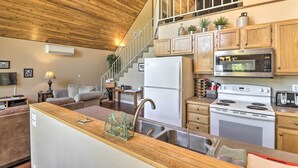 A compact kitchen with a refrigerator, microwave, stove, and sink. There is a wooden staircase leading to an upper level. - Riverfront Hungry Horse House With Large Deck! (Hungry Horse)