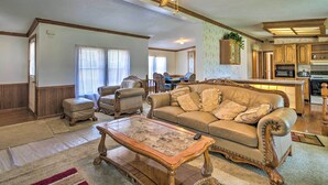 A spacious living room with a large sofa, a coffee table, and a dining area with a kitchen in the background.