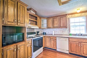 A kitchen with wooden cabinets, a microwave, stove, oven, and dishwasher.