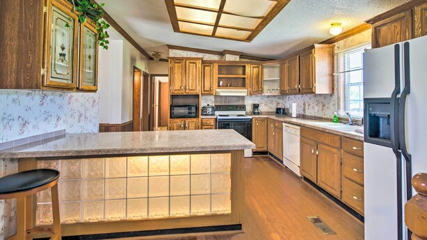 A kitchen with wooden cabinets, a central island with a lighted front, and a ceiling light fixture.