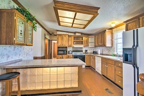 A kitchen with wooden cabinets, a central island with a lighted front, and a ceiling light fixture.