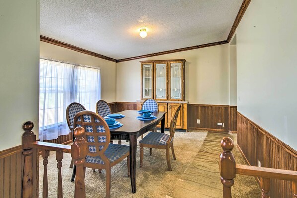 A dining room with a wooden table and chairs, a window with blinds, and a cabinet with glass doors. - Relaxing Prairie Home, 29 Mi to Starkville! (Prairie)