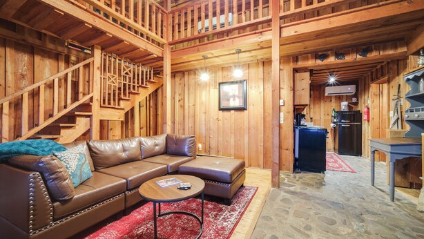 A wooden interior with a leather sofa, a coffee table, and a staircase. - Rustic Maggie Valley Cabin w/ Mountain Views! (Maggie Valley)