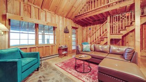 A wooden interior with a sofa, a coffee table, and a blue armchair. - Rustic Maggie Valley Cabin w/ Mountain Views! (Maggie Valley)