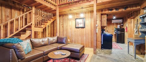 A wooden interior with a leather sofa, a coffee table, and a staircase.