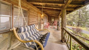 A wooden cabin with a porch, a swing chair, and a view of the surrounding forest. - Rustic Maggie Valley Cabin w/ Mountain Views! (Maggie Valley)