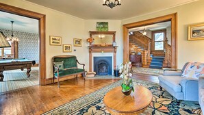 A spacious living room with a fireplace, a billiards table, and a staircase leading to another level.
