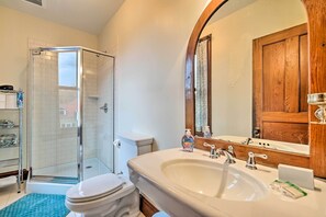 A bathroom with a glass shower enclosure, a white toilet, a large sink with a mirror, and wooden cabinetry. - Pet-friendly Moriah Homestead w/ Fire Pit! (Moriah)