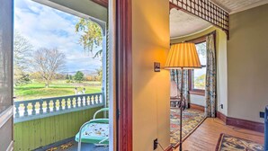 A room with a view of a green landscape, a wooden floor, and a patterned rug.