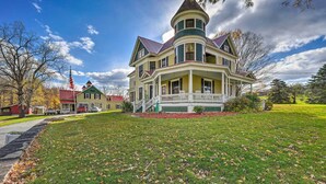 A large, multi-story house with a prominent turret and a wrap-around porch.