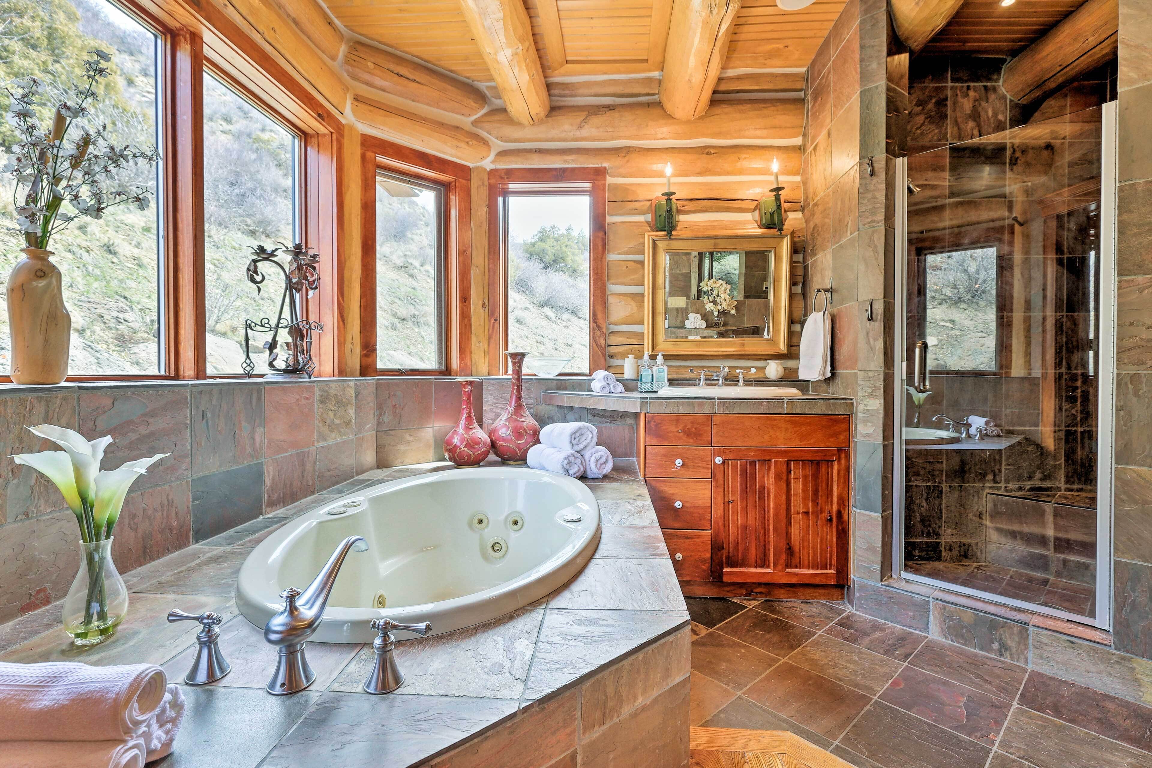 A spacious bathroom with a large bathtub, a glass-enclosed shower, and a wooden vanity.