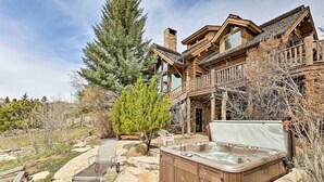 Una casa grande de madera con jacuzzi, patio de piedra y un árbol grande.