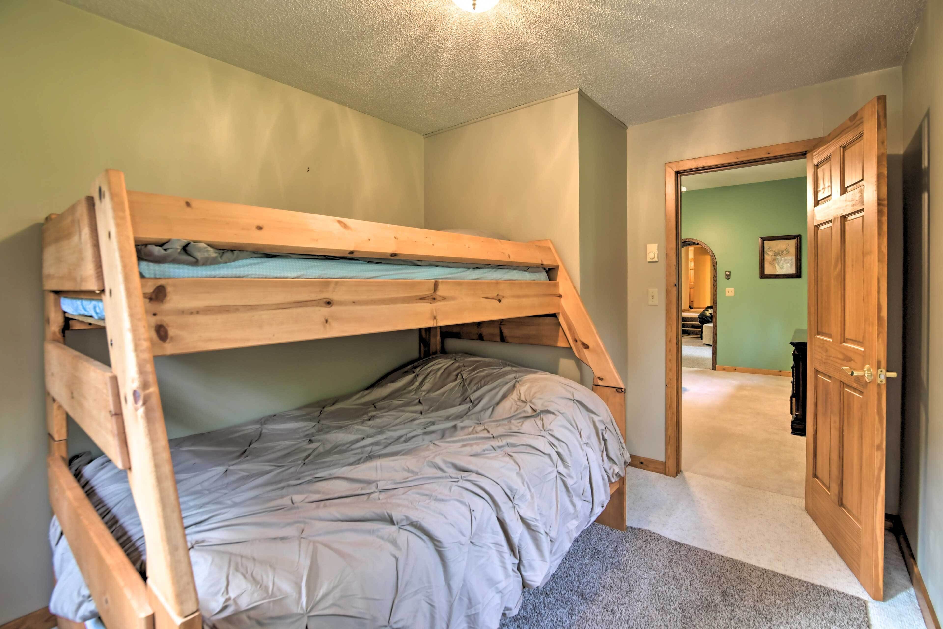Een stapelbed in een kamer met vloerbedekking en een houten deur.
