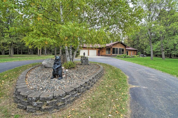 A house with a stone circular driveway, a wooden fence, and a well-maintained lawn. - Spacious Lakefront Home w/ Patio & Boat Dock! (LaPorte)