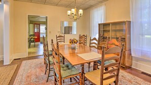 Ein Esszimmer mit Holztisch, Stühlen, einer Chandelier und einem Teppich.