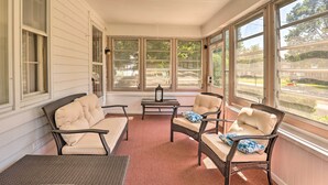 Eine Veranda mit Korbmöbeln und großen Fenstern.