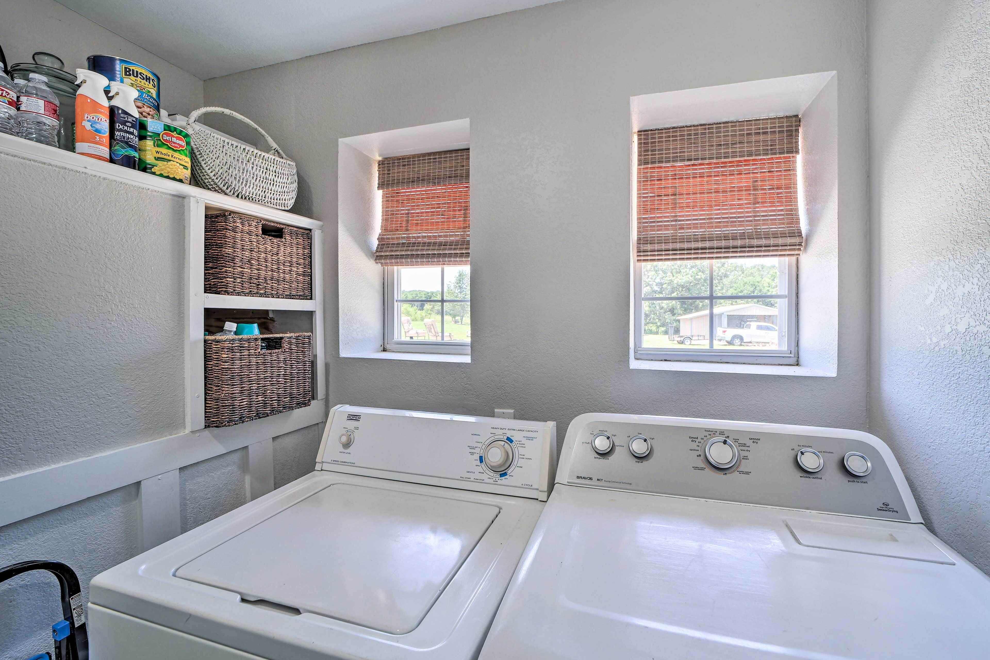 A laundry room with two washing machines, wicker baskets, and a shelf with cleaning supplies.